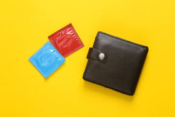 Men's leather wallet with condoms on yellow background