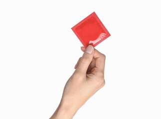 Female hand holding red condom pack isolated on white background