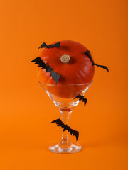 halloween Party. Cocktail glass with pumpkin and bats on orange background