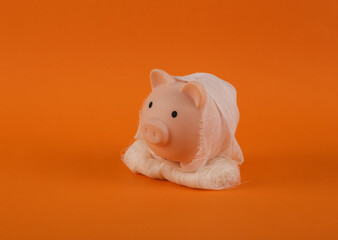 Mummy piggy bank wrapped in bandages on orange background. Trick or treat. Halloween still life