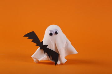 Halloween still life. Ghost with a bat on an orange background