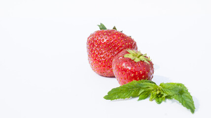 Ripe red strawberries and mint leaves on a white, pastel background