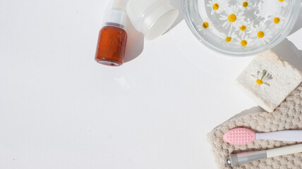 Beauty concept. Cream , cosmetic accessories  and a glass transparent bowl with chamomile flowers on a white pastel background.Flat lay, top view, copy space