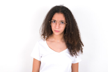 Fototapeta premium young beautiful girl with afro hairstyle wearing white t-shirt over white wall frowning his eyebrows being displeased with something.