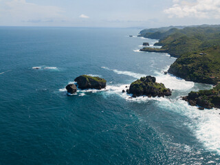 Naklejka premium Coral Island which overgrown by grass on the beach and hit by the wave.the sea water looks clear and blue. Timang island, Yogyakarta, Indonesia