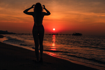 silhouette of a girl with long hair admiring the sunset and sea