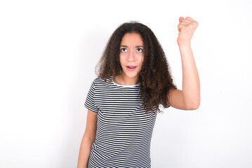 Fierce young beautiful girl with afro hairstyle wearing striped t-shirt over white wall holding...