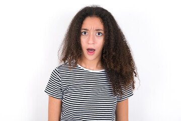 Emotional attractive young beautiful girl with afro hairstyle with opened mouth expresses great surprise and fright, stares at camera. Unexpected shocking news and human reaction.