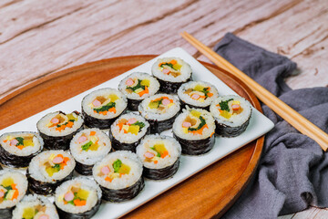 Korean food Gimbap : Rice seasoned with salt and sesame oil and rolled up in a sheet of roasted gim (dried laver) with spinach, carrots, and pickled white radish. The long roll is sliced and served in