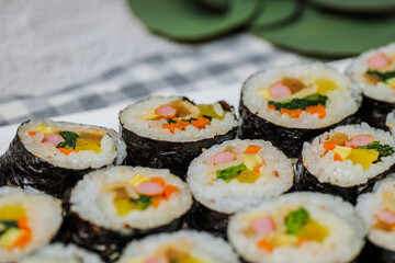 Korean food Gimbap : Rice seasoned with salt and sesame oil and rolled up in a sheet of roasted gim (dried laver) with spinach, carrots, and pickled white radish. The long roll is sliced and served in
