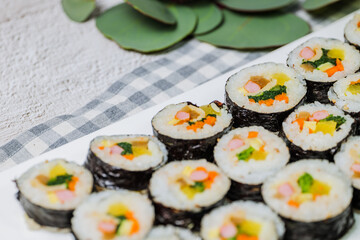 Korean food Gimbap : Rice seasoned with salt and sesame oil and rolled up in a sheet of roasted gim (dried laver) with spinach, carrots, and pickled white radish. The long roll is sliced and served in