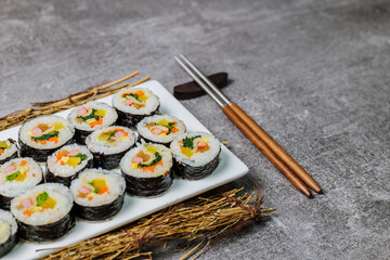 Korean food Gimbap : Rice seasoned with salt and sesame oil and rolled up in a sheet of roasted gim (dried laver) with spinach, carrots, and pickled white radish. The long roll is sliced and served in
