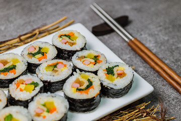 Korean food Gimbap : Rice seasoned with salt and sesame oil and rolled up in a sheet of roasted gim (dried laver) with spinach, carrots, and pickled white radish. The long roll is sliced and served in