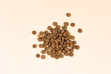 A handful of dry food for cats and dogs on a beige background. View from above - 514650030