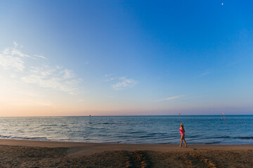 Obraz premium Summer woman vacations concept. girl walking on beach and admiring the sea and sunset.