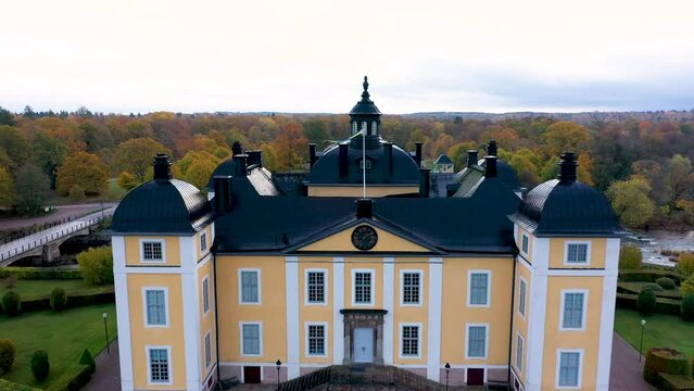 Castle or royal palace by lake or water with a beautiful autumn park. Beautiful building aerial drone shot from above. 