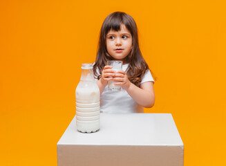 Portrait of beautiful girl with glass of milk on yellow background