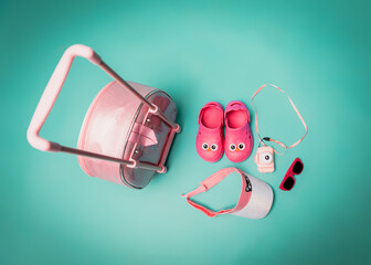 on a turquoise background, a children's suitcase, sunglasses, a hat, a camera and crocs. children's...