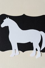 white paper horse on black paper