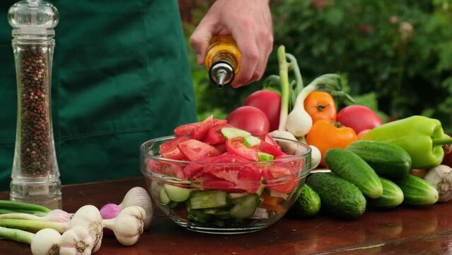 Olive oil pouring over dish with organic ingredients. Summer salad in bowl. Vegetable fresh salad with tomatoes, cucumbers, peppers, scallion, onion, carrot, garlic Pour Olive Oil on salad slow motion
