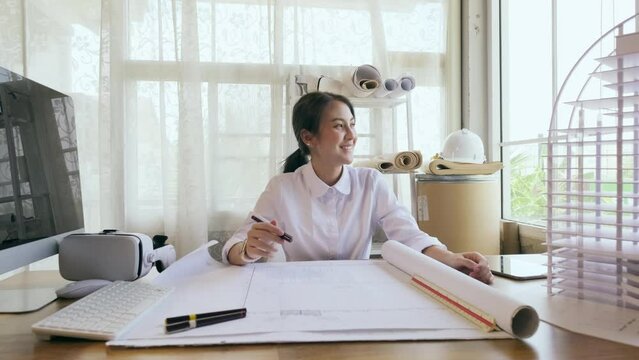 4K resolution slow motion, Happy smile Asian female Architect with blueprint in office. Architect woman working in workplace.