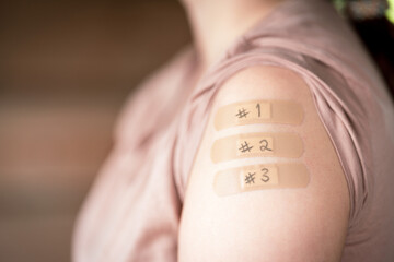 female with rolled up shirt sleeve to show the bandaid after the 1, 2 and 3 coronavirus vaccines...