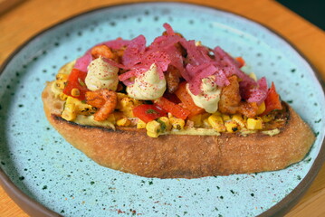 Leckeres Sandwich mit Garnelen, Mais, roter Beete, und Paprika auf einem Keramikteller