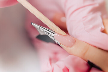 Manicure process. The master forms an artificial nail from a special gel using a bamboo stick.