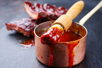 Hot and spicy barbecue sauce in a casserole with spare ribs in background