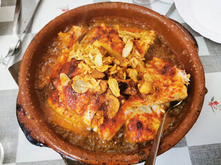 Clay pot on tablecloth with Valderas-style cod, Leon, Spain 
