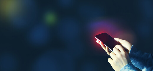 Person using a smartphone on a dark blue background
