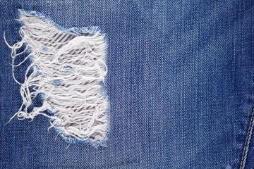 Blue jeans denim background texture. Torn jeans fabric material surface