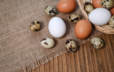Fototapeta na wymiar Different types of eggs. Chicken and quail eggs on the table. Bamboo mat, burlap and wicker basket. Top view, place for text. Easter or healthy food concept.
