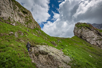 Mountain hiking Trail Road. Between Italy and Austria: near Volaia Lake Raunchkofer Mountain (Lago di Volaia Monte Rauchkofel). A little traveler climbs in the mountains with sticks.