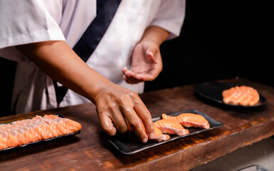 Chef's hand holding fresh piece of salmon.Closeup of chef hands preparing japanese food. Japanese...