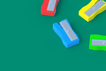Scattered pencil sharpeners on green background. Stationery accessories. Tool for school. Copy space. 3d render
