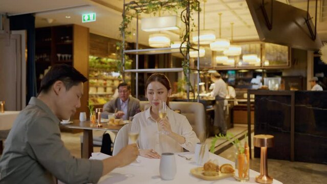 Asian couple having dinner at an upscale restaurant. They enjoy dinner and champagne in this night.