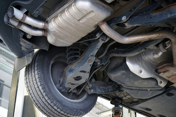 Modern car in a car service on a lift. Suspension elements and exhaust system. Auto parts and car...