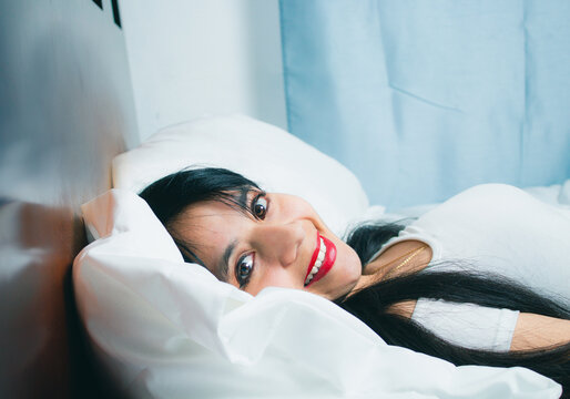 happy latin young woman waking up in bed