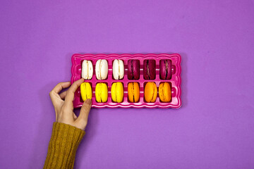 closeup hand woman holding a French colorful Macarons Cookies