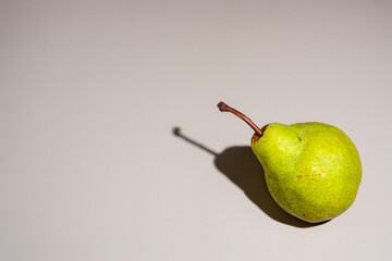 green pear casts a shadow on a gray background, copy space
