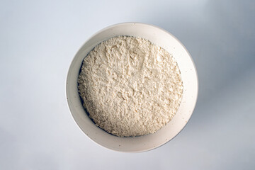 flour in white ceramic plate on white background with copy space