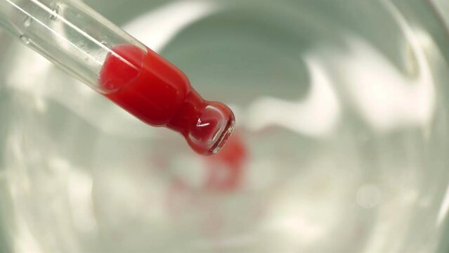 A drop of liquid falling from a pipette into water