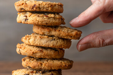 close up of a vertical stack of homemade cookies with a hand choosing one