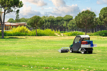 Golf course and a vehicle collecting golf balls. Ballpicker on driving range of golf club