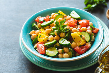 Chickpea salad with tomatoes, cucumber, parsley, onions in a plate, selective focus. Healthy vegetarian food, oriental and Mediterranean cuisine. Chick peas salad