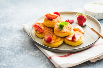 Cottage cheese pancakes, ricotta fritters or syrniki with mint and strawberries. Healthy and delicious morning breakfast.