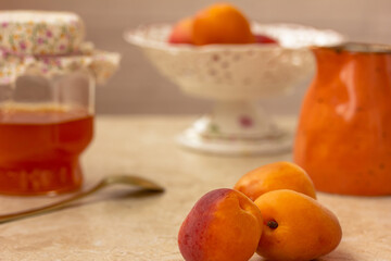 Naklejka na ściany i meble Ripe Apricots, Homemade jam in a glass, a spoon on a kitchen table. Preserved fruit.