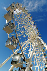Ferris wheel against blue sky. Modern white ferris wheel. Bottom view.