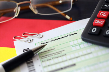 German income tax return form with pen and european euro money bills lies on flag close up....